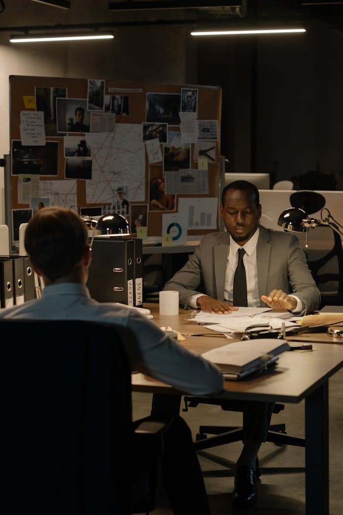 Two men engaged in a serious discussion in a modern office at night.